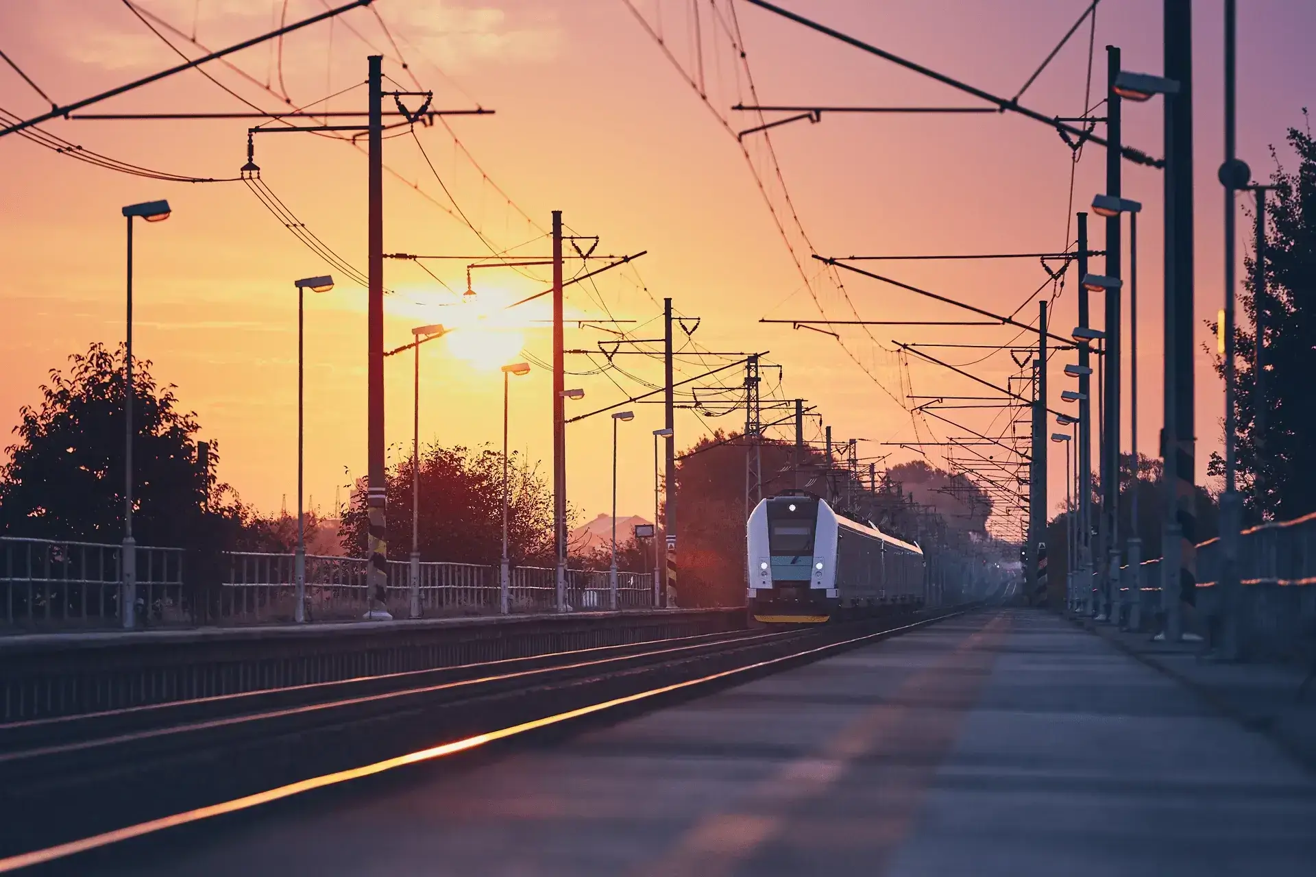 Passenger train on railway tracks at sunrise, powered by OLE